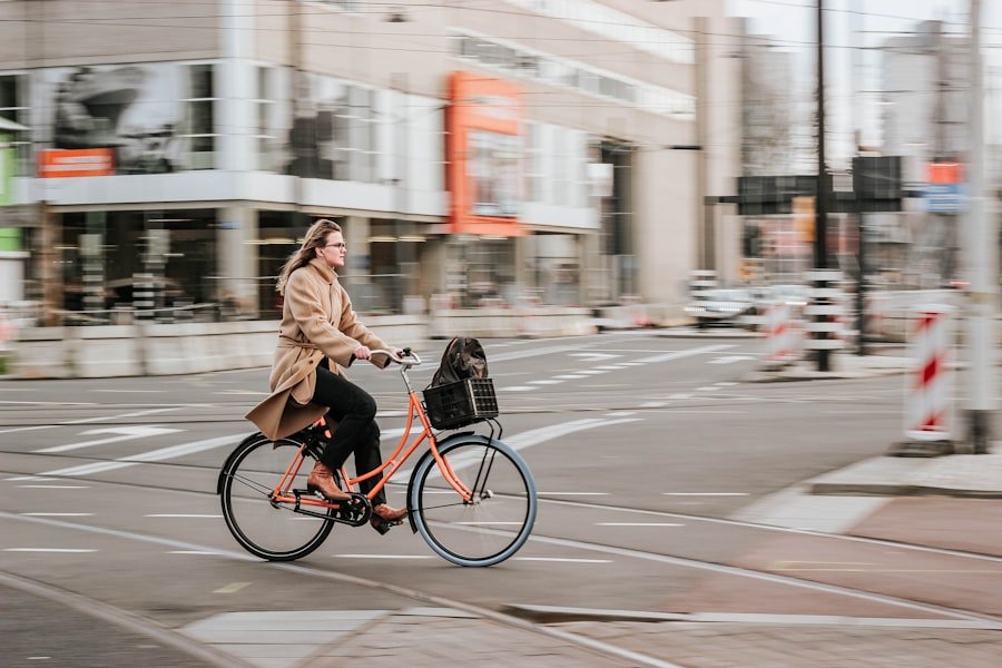 Kvinde i brun frakke cykler elegant på sort citybike i bymiljøet